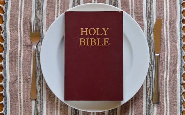 Bible on a dinner plate with silverware in lent.